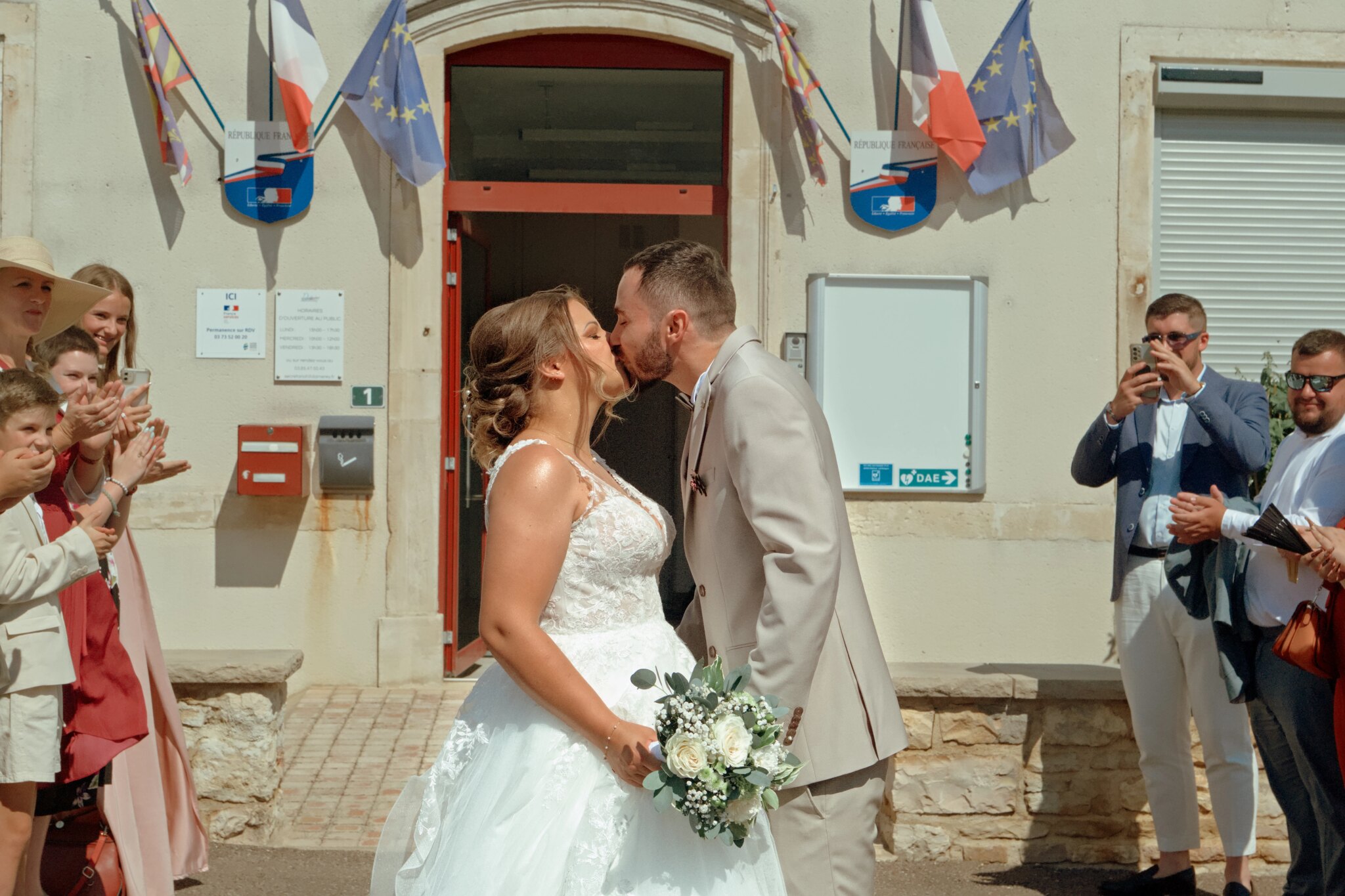 Photo du couple marié s'embrassant devant la mairie