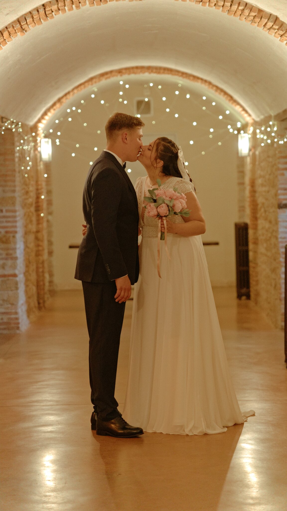Photo de mariage d'un couple s'embrassant sous les arches intérieur d'un bâtiment